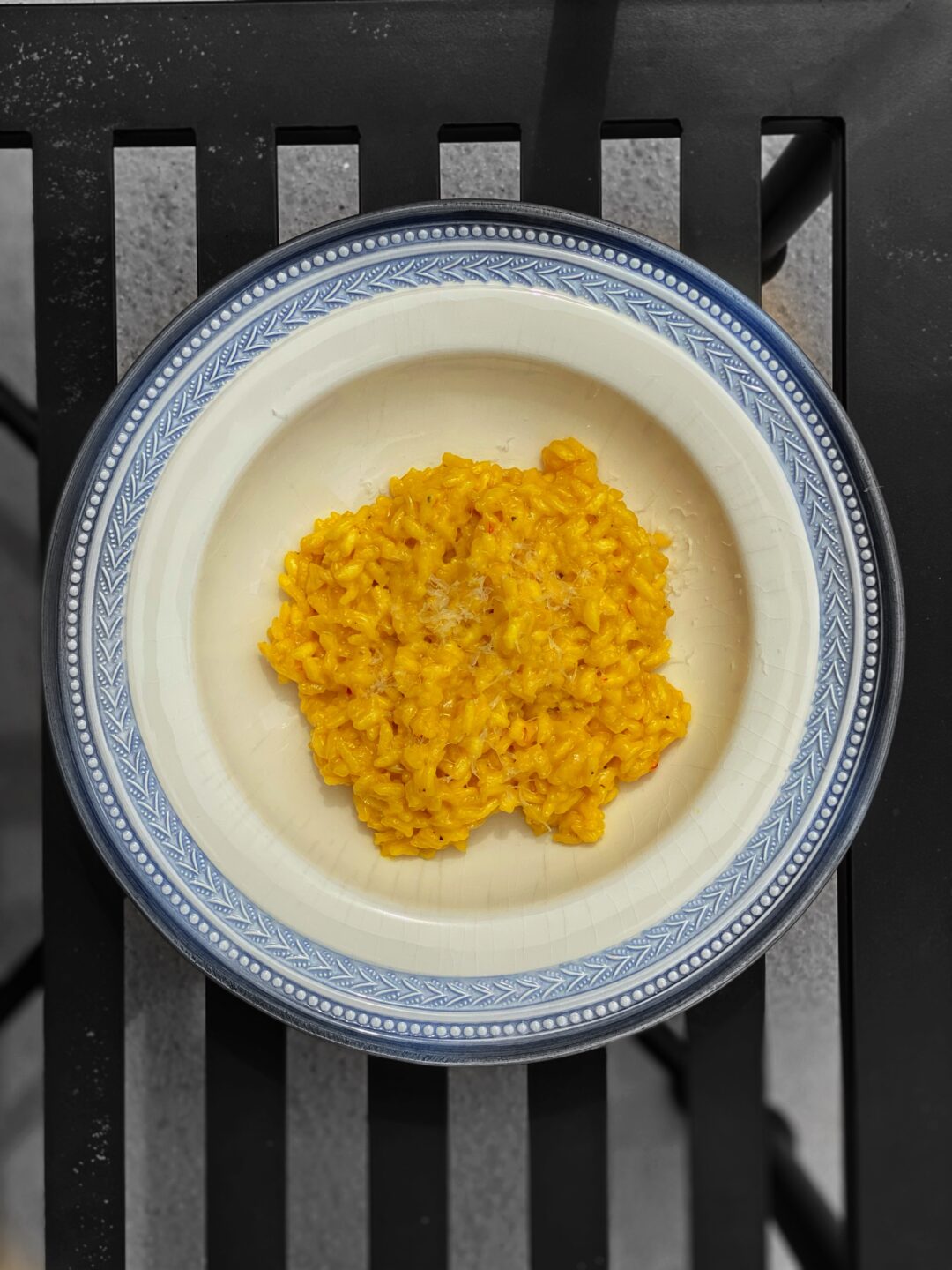 overhead of saffron risotto in a white bowl with a blue rim