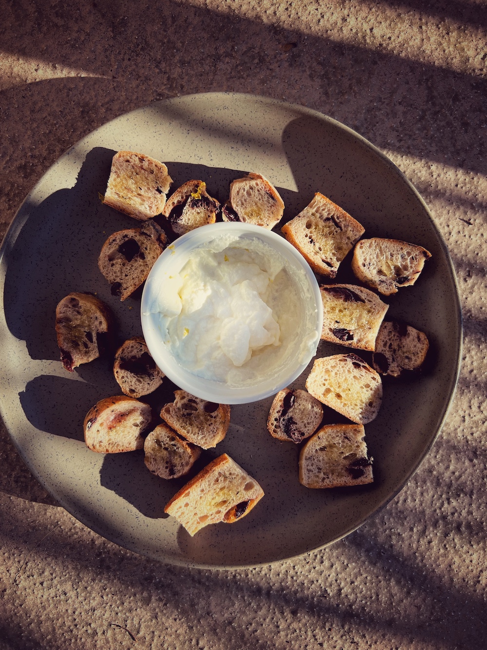 overhead of white bowl with ricotta and sliced bread on brown plate
