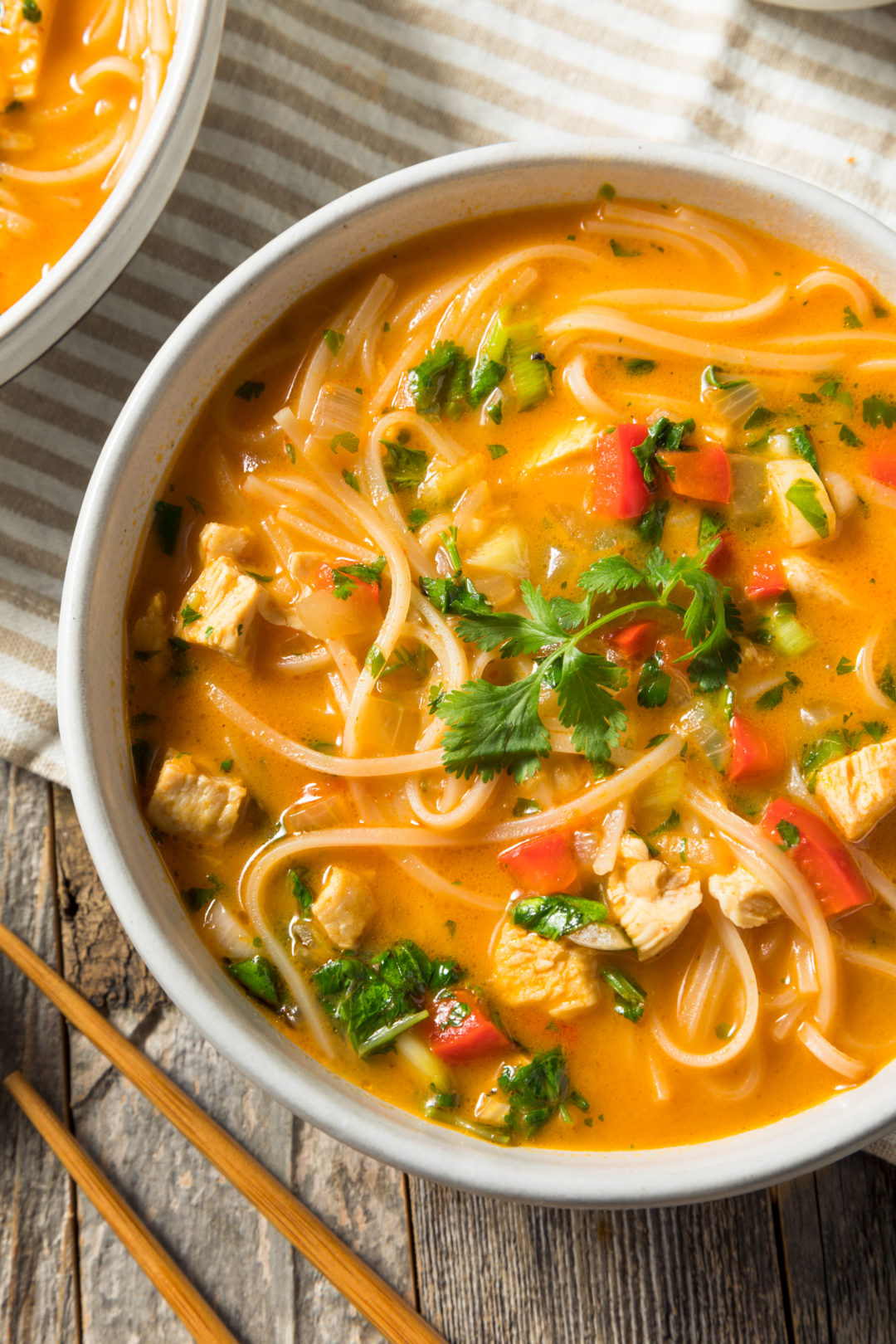 bowl of red curry with chicken, noodles and basil