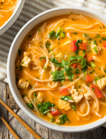 bowl of red curry with chicken, noodles and basil