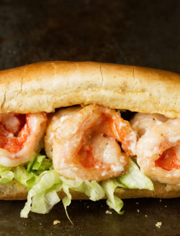 front-view closeup of a fried shrimp po' boy sandwich on a long French roll