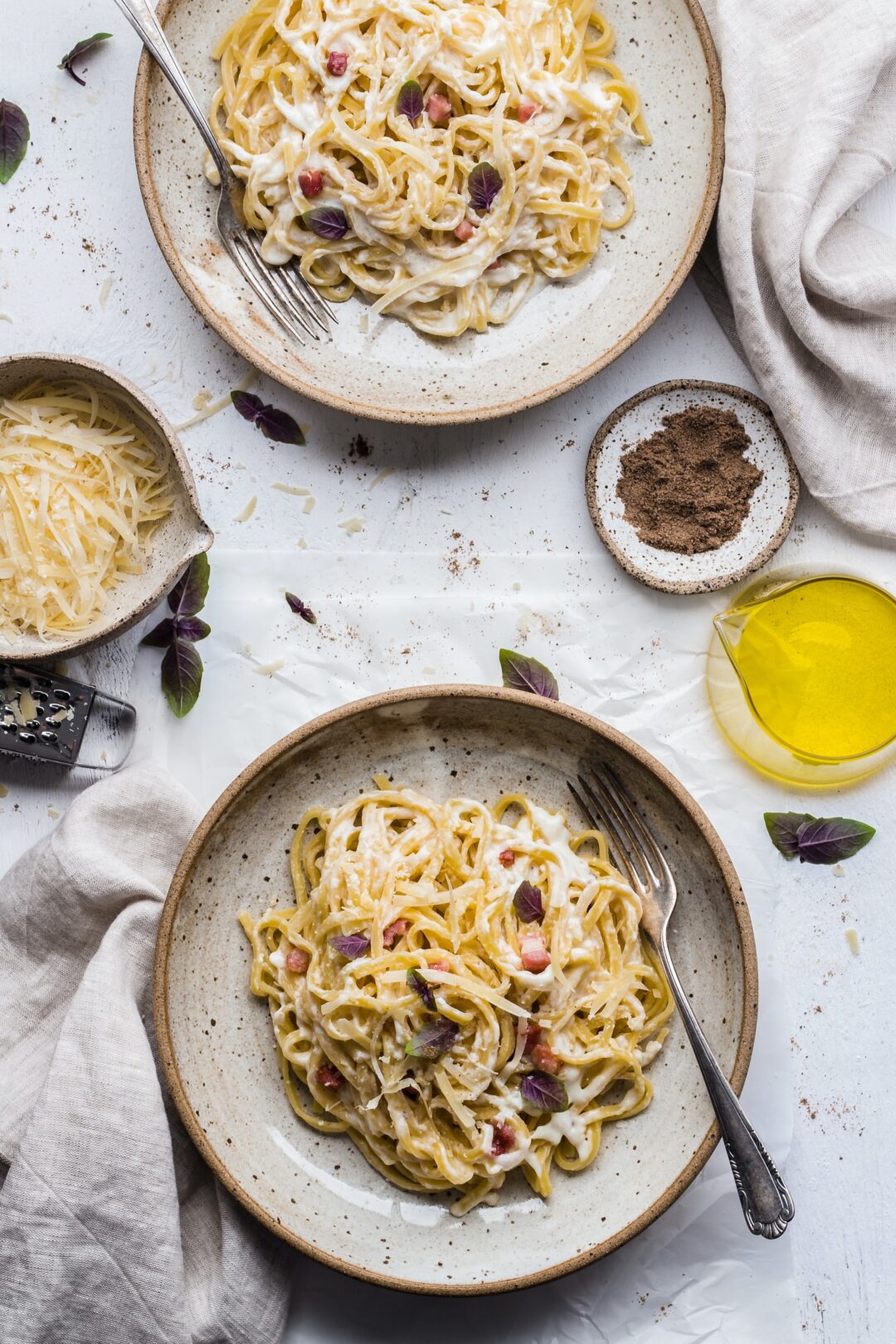 overhead view of spaghetti with a creamy carbonara sauce, garnished with grated parmesan cheese