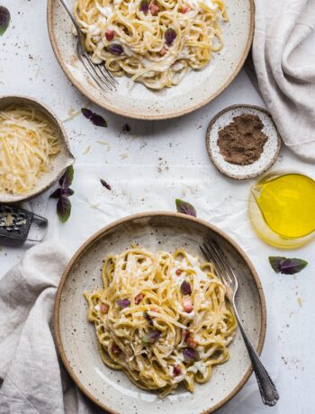 overhead view of spaghetti with a creamy carbonara sauce, garnished with grated parmesan cheese