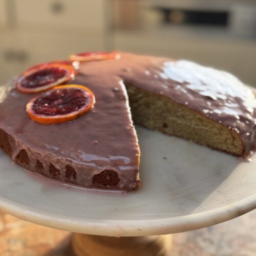 Side view of blood orange cardamom cake on marble cake stand