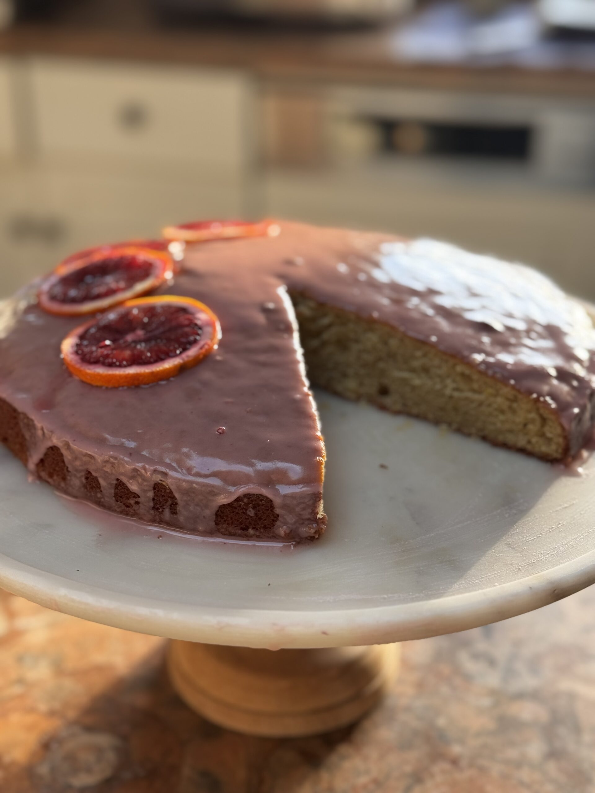 Side view of blood orange cardamom cake on marble cake stand