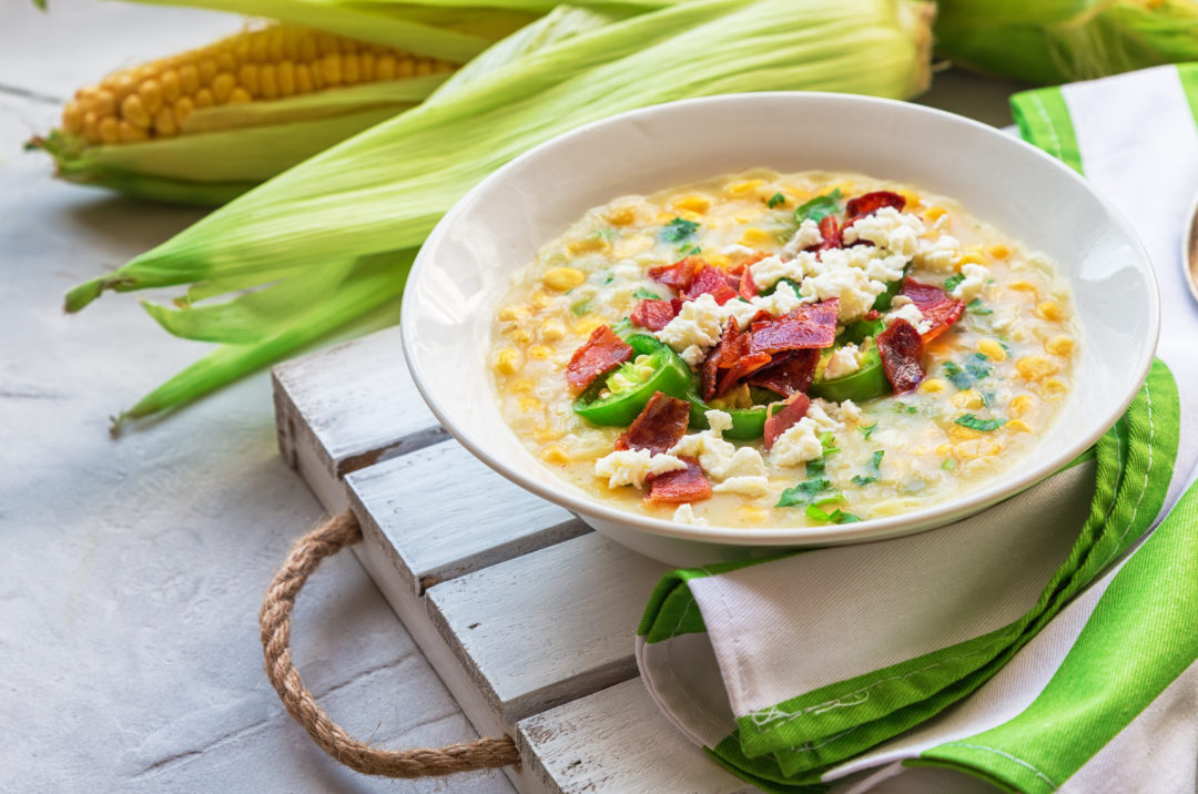 side view of Mexican street corn soup, topped with cotija cheese, bacon bits and jalapeno slices