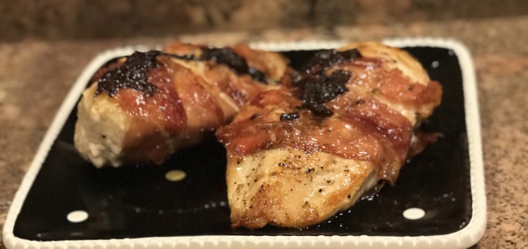side view of prosciutto-wrapped chicken garnished with crispy sage