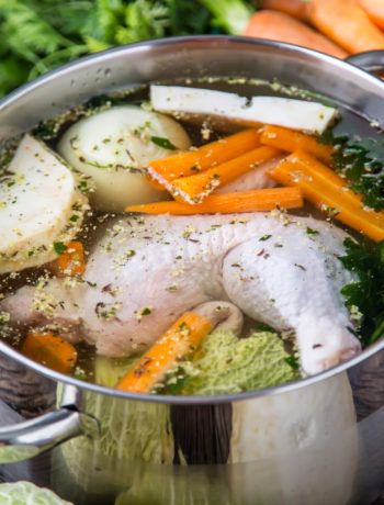 top view of chicken broth on wooden table with vegetables