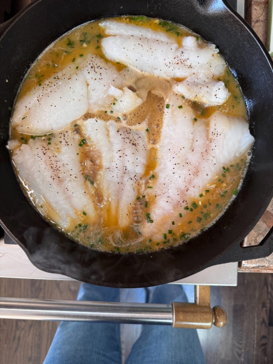overhead photo of cooked miso cod in butter sauce in cast iron skillet