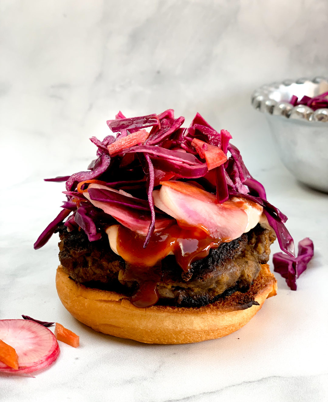 side-view of open-faced asian beef burger topped with hoisin ketchup sauce and coleslaw