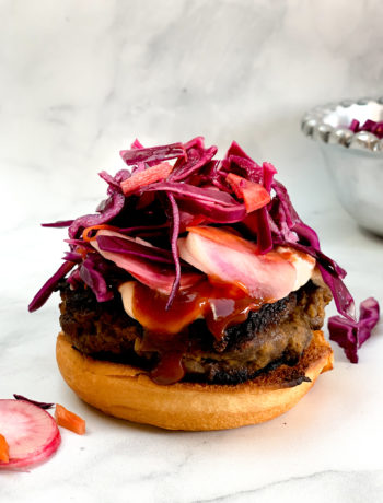 side-view of open-faced asian beef burger topped with hoisin ketchup sauce and coleslaw