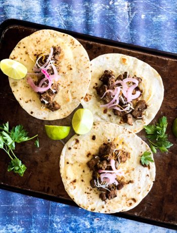 overhead skillet pork tacos, garnished with pickled red onions, cilantro and lime on grilled flour tortillas