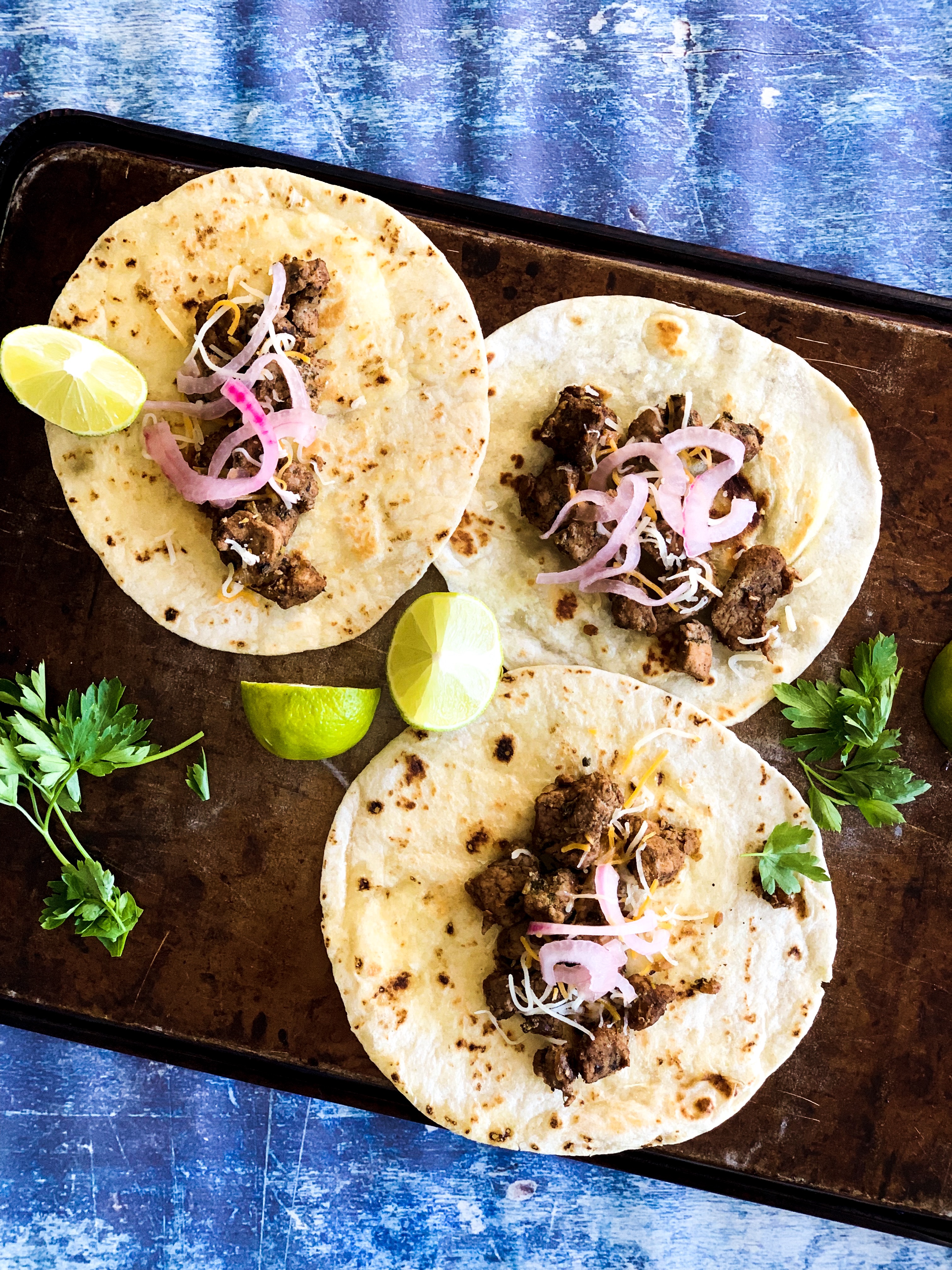 overhead skillet pork tacos, garnished with pickled red onions, cilantro and lime on grilled flour tortillas