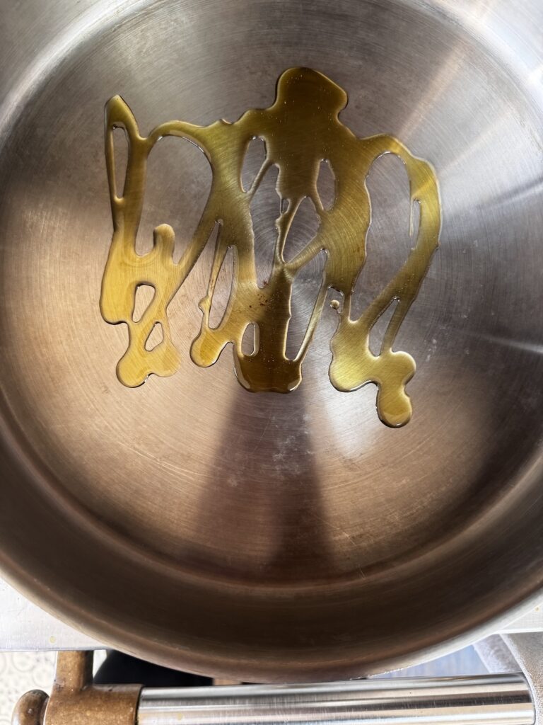 Stainless steel pan on stove with olive oil