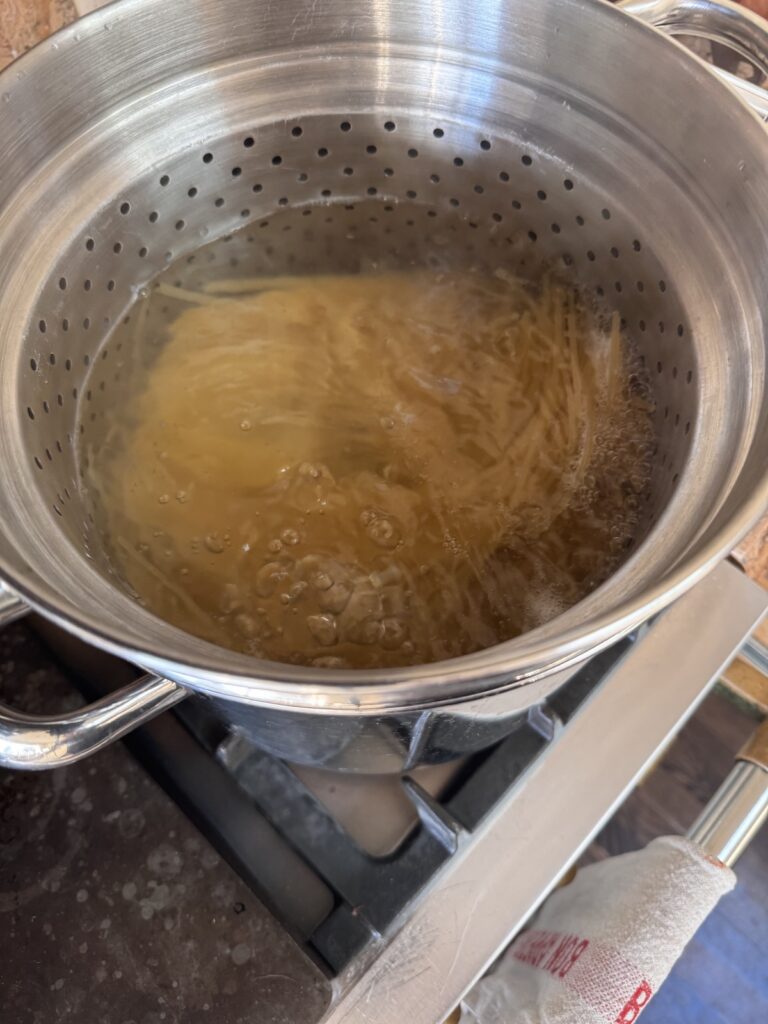 large pot of water on stove with spaghetti