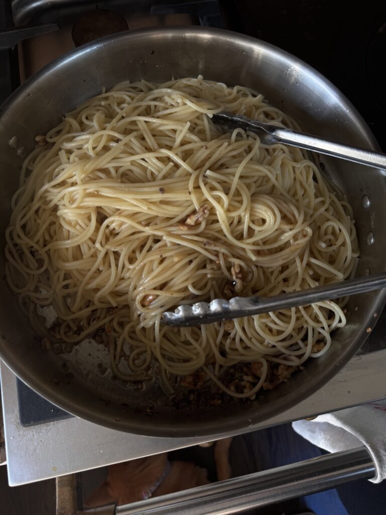 spaghetti in skillet on stove with tongs.