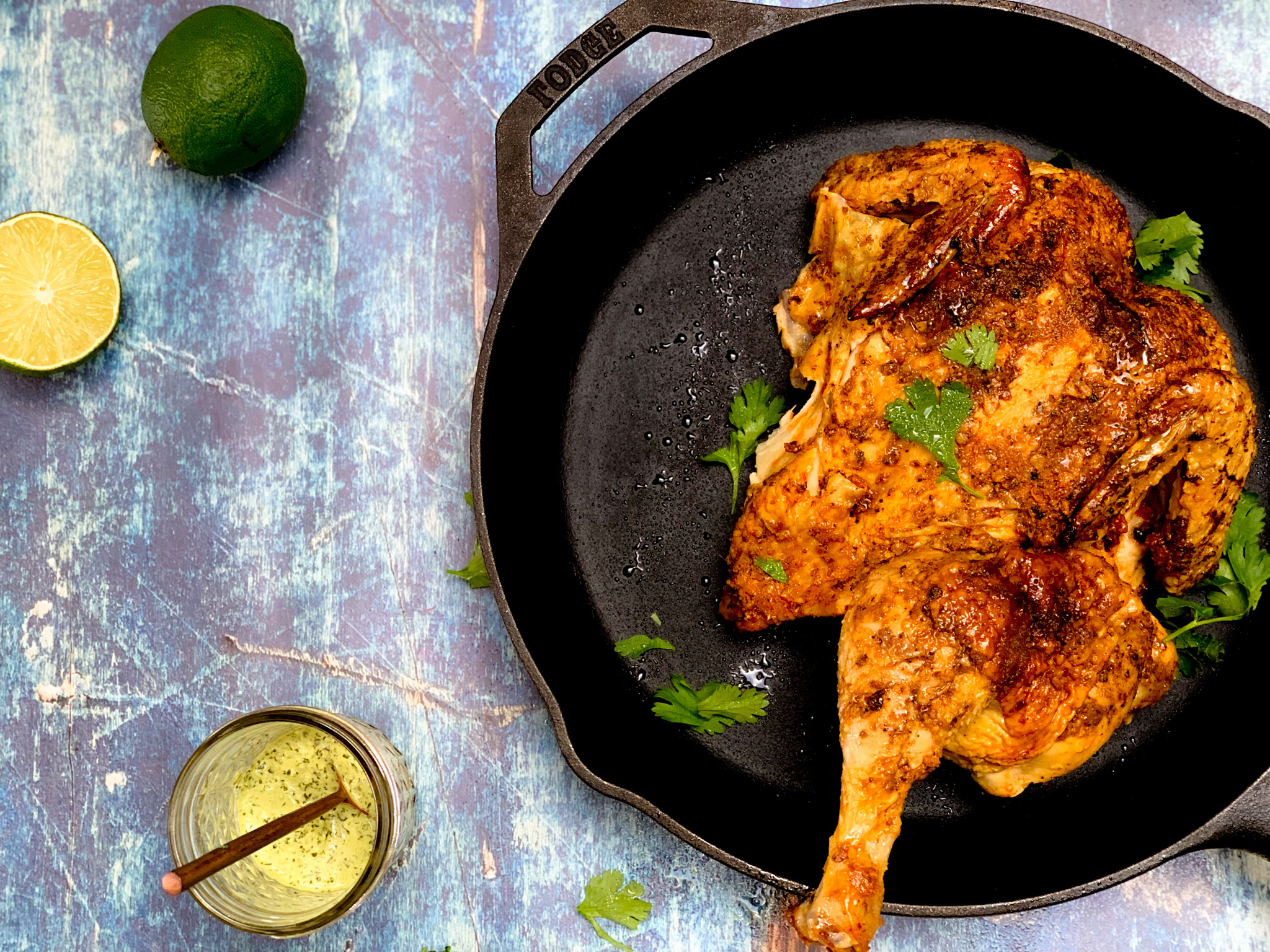 overhead of chicken in skillet with lime and green dressing