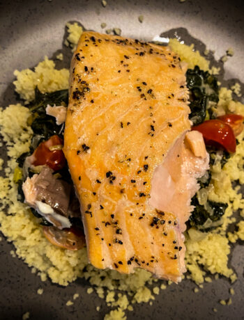 close up overhead view of salmon over couscous on brown plate