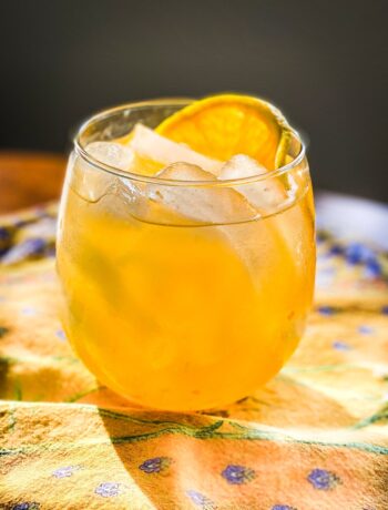 drink in a small glass on yellow tablecloth with orange slice