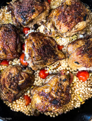 overhead of chicken in pan with couscous and tomatoes