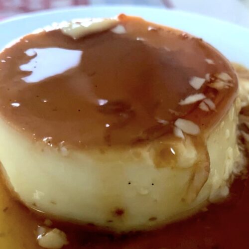 Side view of creme caramel on a plate with caramel sauce