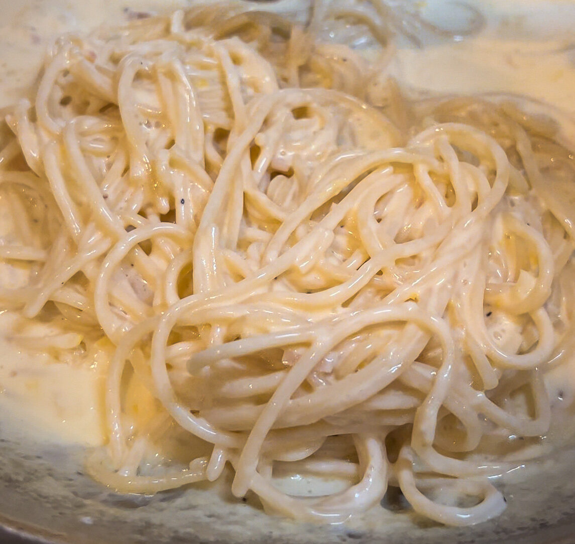 overhead of spaghetti in a creamy sauce in a pan