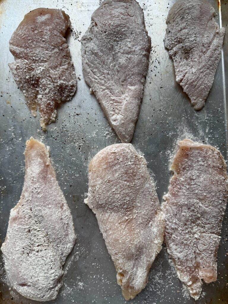 raw chicken breasts on baking sheet