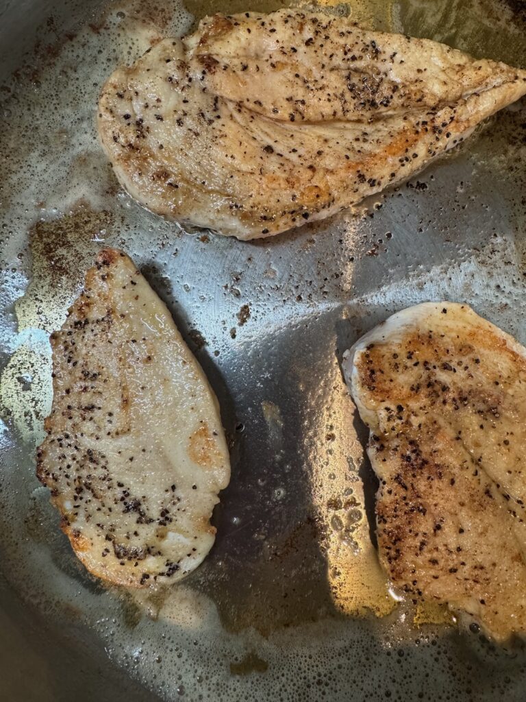 cooked chicken breasts in a stainless steel pan